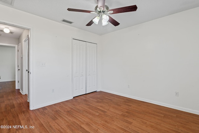 unfurnished bedroom featuring a closet, hardwood / wood-style flooring, and ceiling fan