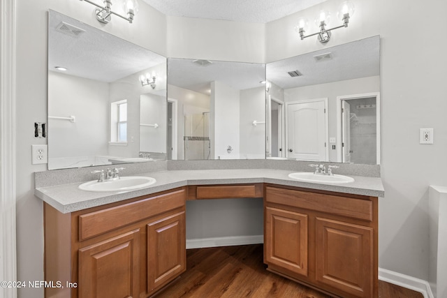 bathroom featuring vanity, a shower with door, wood-type flooring, and a textured ceiling