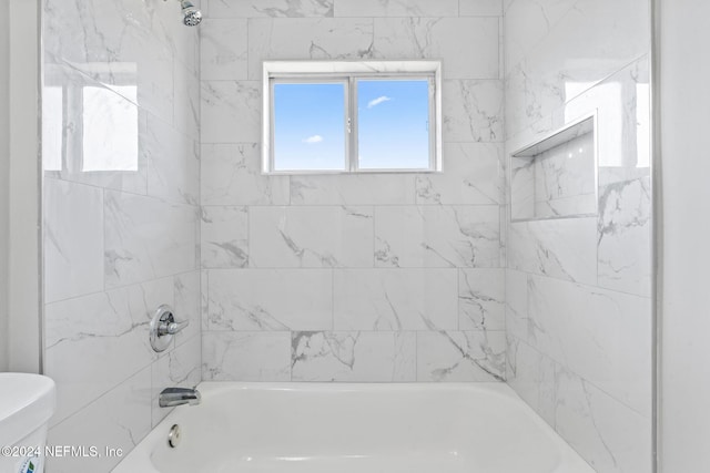 bathroom featuring toilet and tiled shower / bath