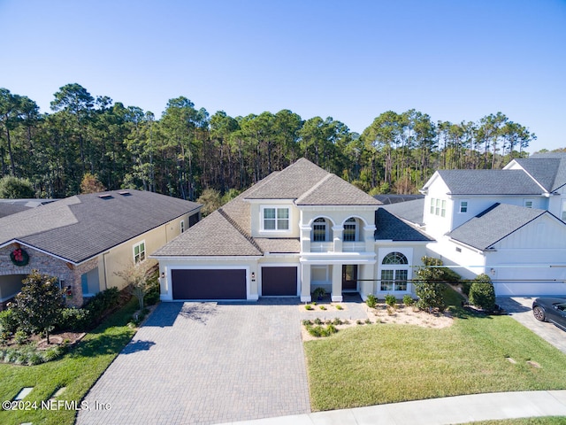 view of front of home featuring a garage, a balcony, and a front yard