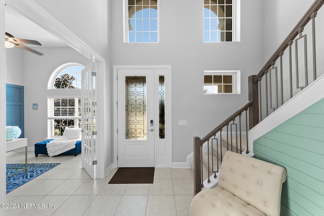 tiled foyer entrance featuring ceiling fan and a towering ceiling