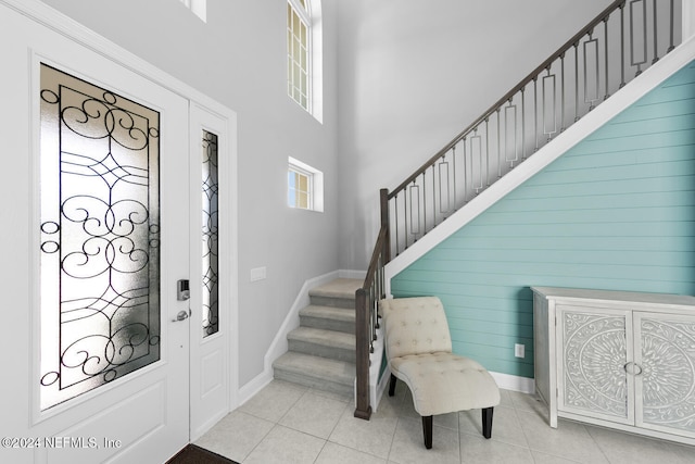 tiled foyer featuring a towering ceiling and wood walls