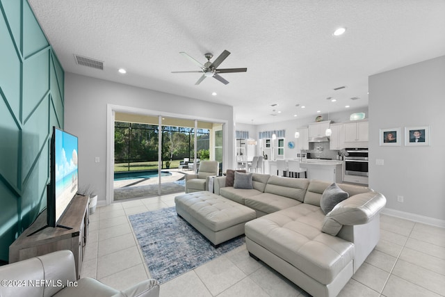 living room featuring ceiling fan, light tile patterned floors, and a textured ceiling