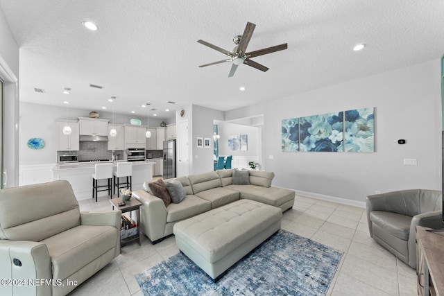 living room with ceiling fan, light tile patterned floors, and a textured ceiling