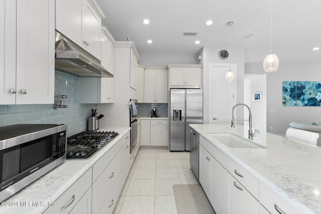 kitchen featuring white cabinetry, light stone countertops, sink, decorative light fixtures, and appliances with stainless steel finishes