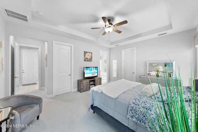 carpeted bedroom with a raised ceiling, ceiling fan, and a textured ceiling