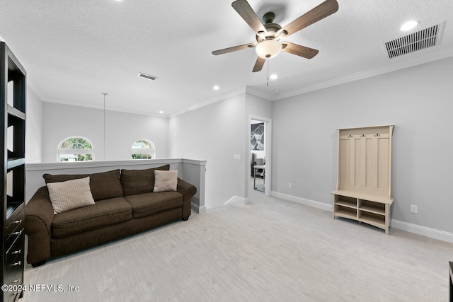 living room featuring light carpet, ceiling fan, a textured ceiling, and ornamental molding