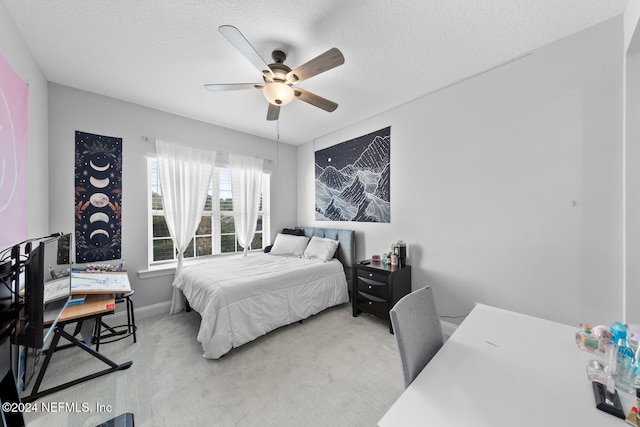 bedroom featuring ceiling fan, light colored carpet, and a textured ceiling