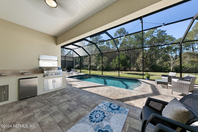 view of pool featuring a lanai, area for grilling, a patio area, and exterior kitchen