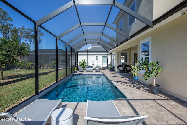 view of pool featuring a lawn, glass enclosure, and a patio