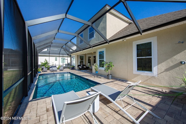 view of swimming pool featuring glass enclosure, outdoor lounge area, and a patio