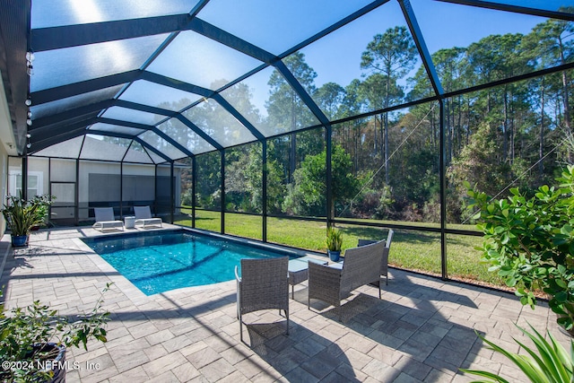 view of pool with a lawn, glass enclosure, and a patio