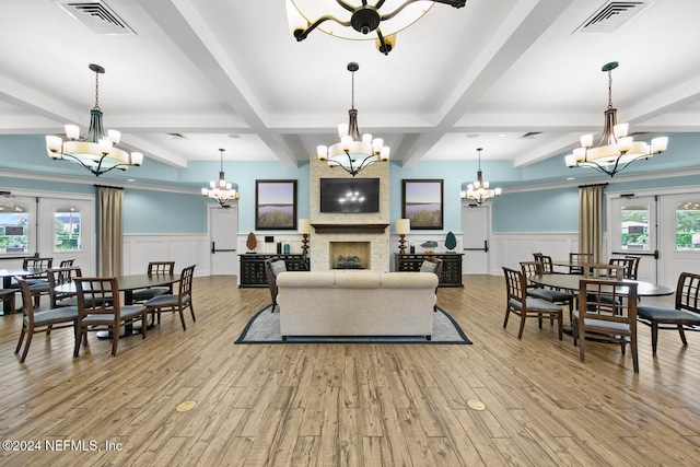 living room with a large fireplace, plenty of natural light, beamed ceiling, and light hardwood / wood-style floors