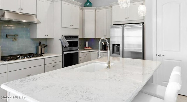 kitchen with white cabinetry, appliances with stainless steel finishes, sink, and a center island with sink