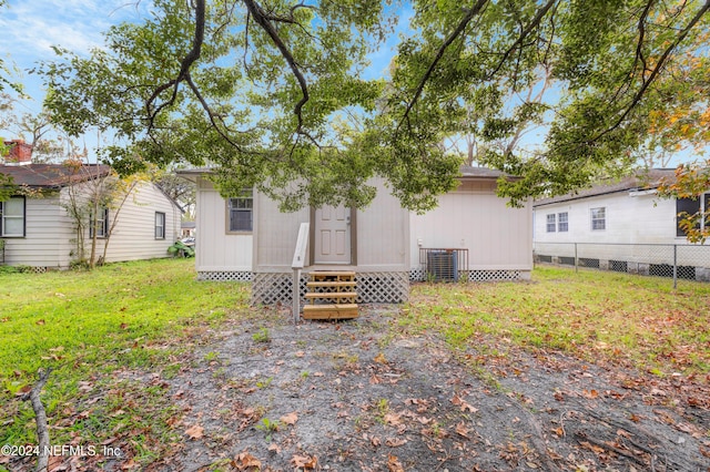 rear view of property featuring cooling unit and a yard