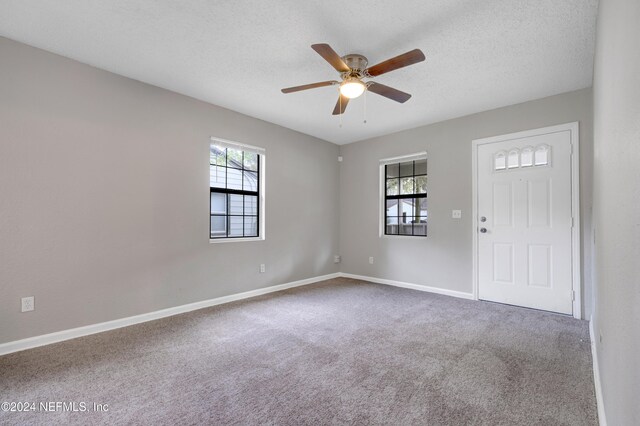 carpeted spare room with a textured ceiling and ceiling fan