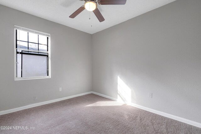 carpeted empty room featuring ceiling fan and a textured ceiling