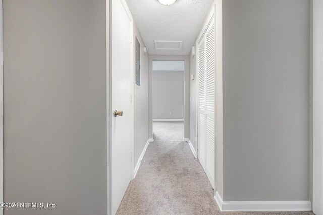 hall featuring light carpet and a textured ceiling