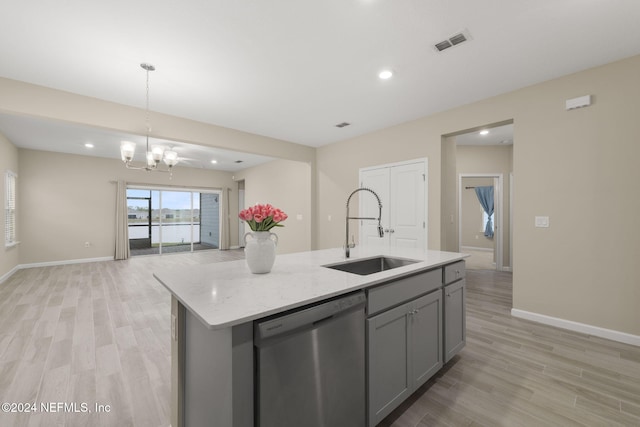 kitchen featuring sink, gray cabinets, light stone counters, stainless steel dishwasher, and a center island with sink