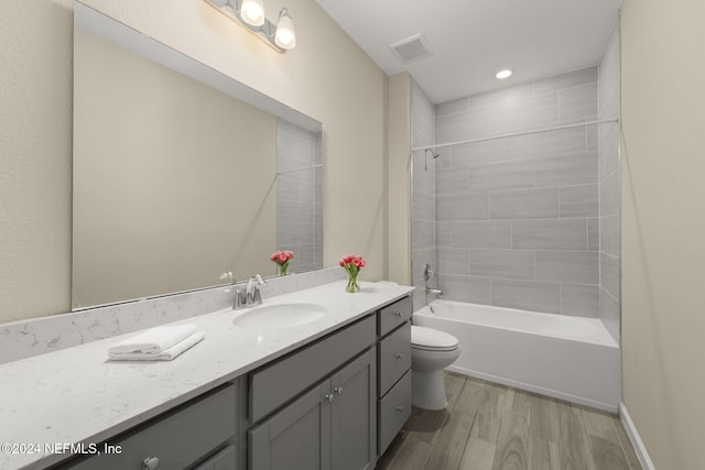 full bathroom featuring tiled shower / bath combo, hardwood / wood-style flooring, toilet, and vanity