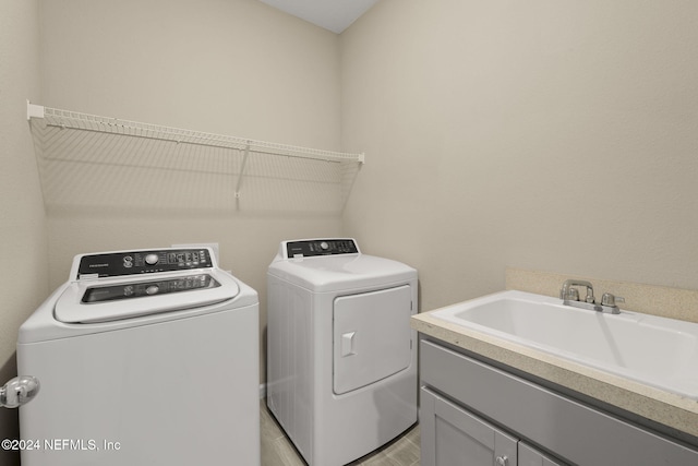 washroom featuring washer and dryer, sink, and cabinets