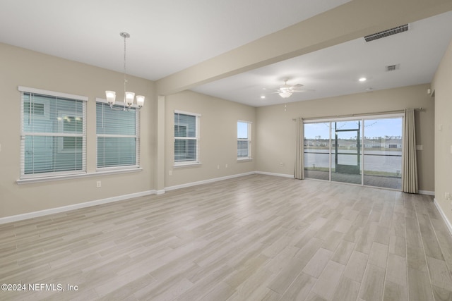 empty room with light wood-type flooring and ceiling fan with notable chandelier