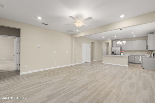 unfurnished living room with ceiling fan with notable chandelier and light hardwood / wood-style floors