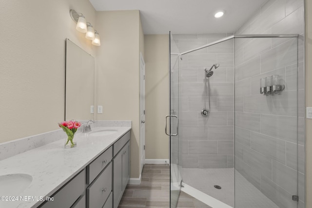 bathroom featuring a shower with shower door and vanity