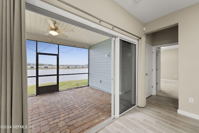 unfurnished sunroom with a water view and ceiling fan