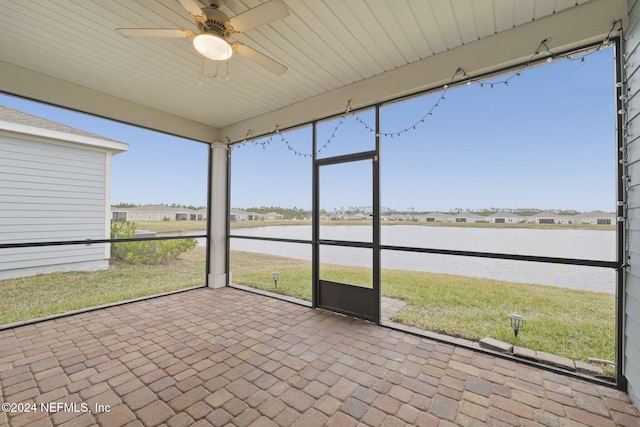 unfurnished sunroom with ceiling fan and a water view