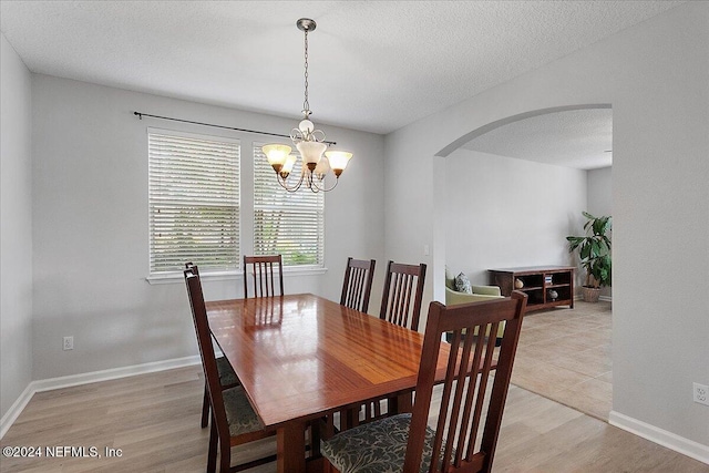 dining space with a chandelier, a textured ceiling, and light wood-type flooring