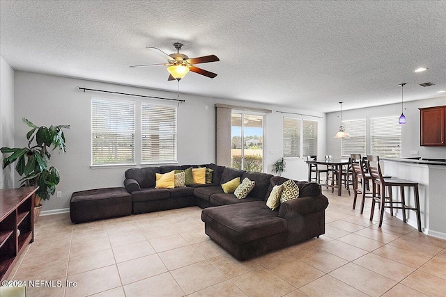 living room featuring a textured ceiling, ceiling fan, and light tile patterned flooring