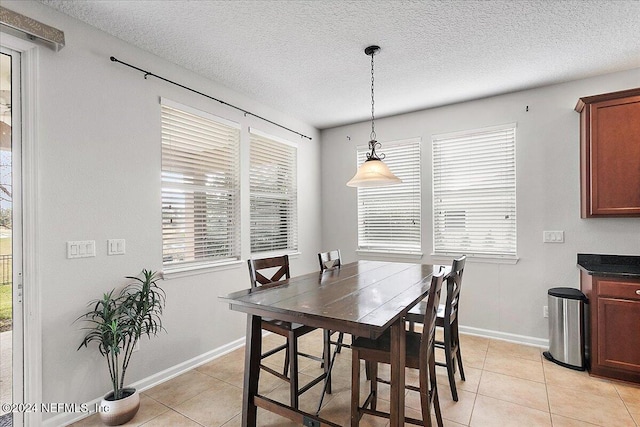 tiled dining area featuring a healthy amount of sunlight and a textured ceiling