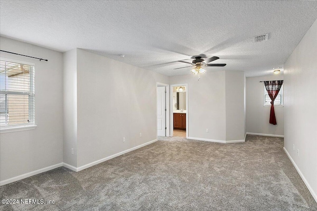 carpeted spare room with ceiling fan, a healthy amount of sunlight, and a textured ceiling