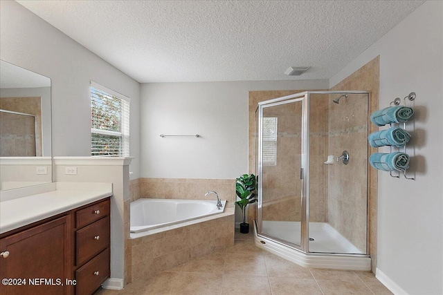 bathroom with tile patterned flooring, vanity, independent shower and bath, and a textured ceiling