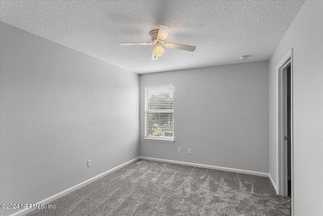 spare room with dark colored carpet, ceiling fan, and a textured ceiling