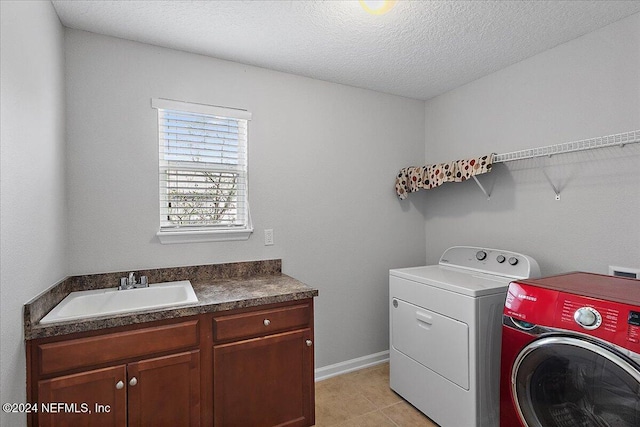 washroom with cabinets, a textured ceiling, sink, light tile patterned floors, and separate washer and dryer