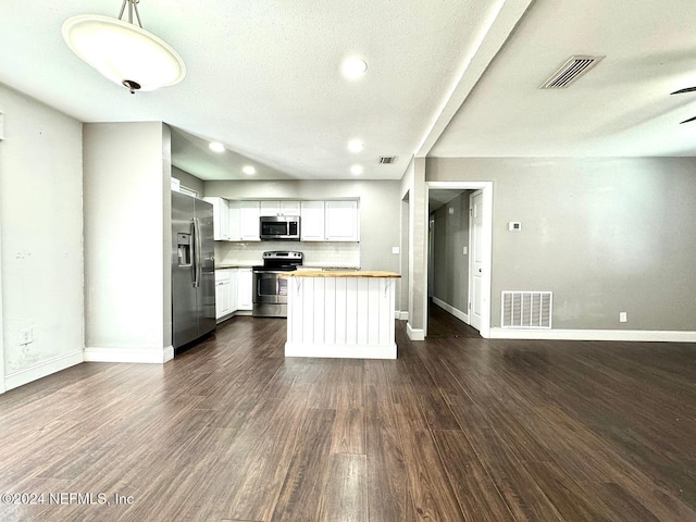 kitchen featuring white cabinets, hanging light fixtures, a textured ceiling, appliances with stainless steel finishes, and dark hardwood / wood-style flooring