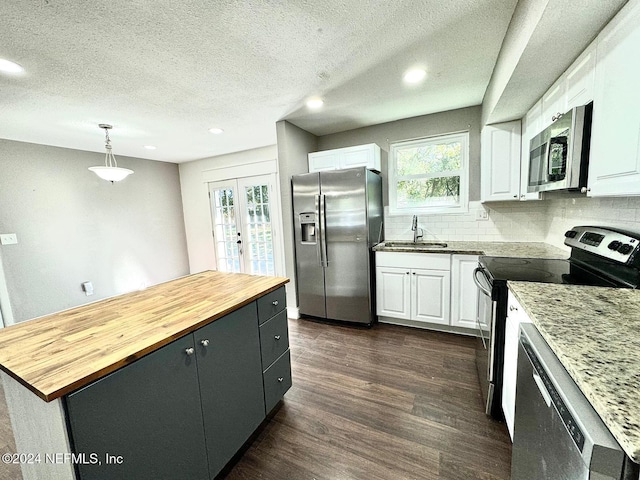 kitchen with a center island, dark wood-type flooring, decorative light fixtures, white cabinetry, and stainless steel appliances