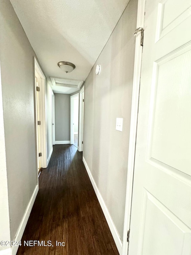 hall with dark hardwood / wood-style flooring and a textured ceiling