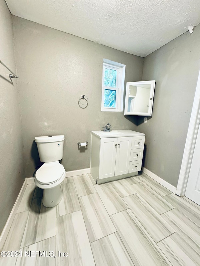 bathroom with vanity, toilet, wood-type flooring, and a textured ceiling