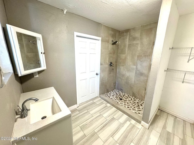 bathroom with a tile shower, sink, and a textured ceiling