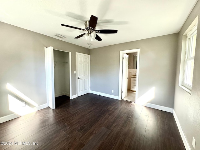 unfurnished bedroom featuring dark hardwood / wood-style floors, ceiling fan, ensuite bath, and a closet