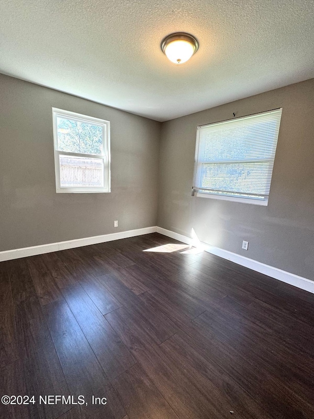 empty room with a textured ceiling and dark hardwood / wood-style flooring