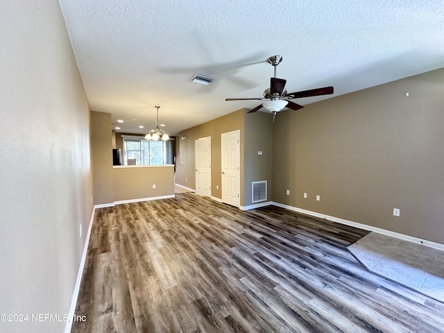 unfurnished living room featuring a textured ceiling, ceiling fan with notable chandelier, and dark wood-type flooring