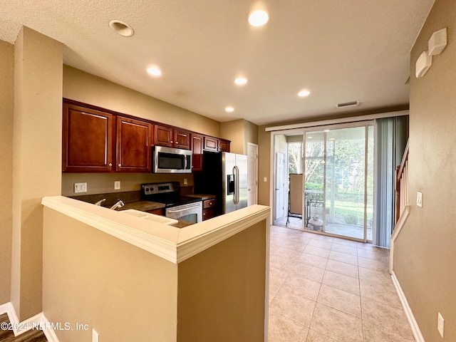 kitchen featuring kitchen peninsula, light tile patterned floors, and stainless steel appliances