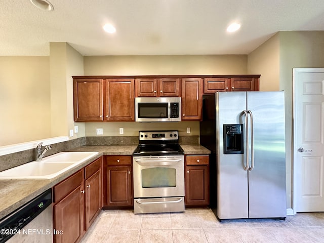 kitchen with sink, light tile patterned floors, and stainless steel appliances