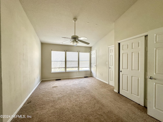 interior space with ceiling fan, lofted ceiling, and a textured ceiling