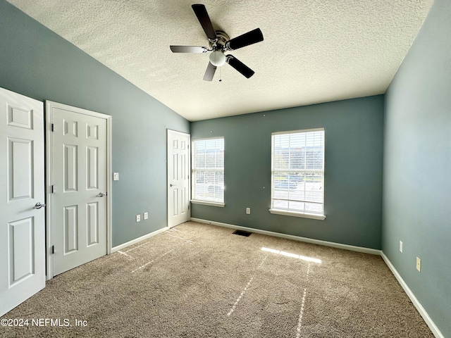 unfurnished bedroom with light carpet, a textured ceiling, and ceiling fan