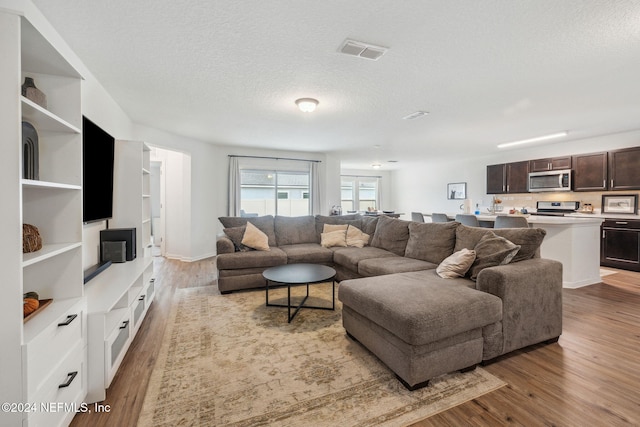 living room with a textured ceiling and light hardwood / wood-style flooring